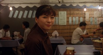 Movie still from “Gamera 3: Revenge of Iris” (1999), directed by Shûsuke Kaneko – A woman holding a glass of beer in a restaurant; Close Up shot, Over the shoulder angle