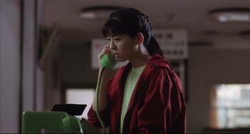 Movie still from “Gamera 3: Revenge of Iris” (1999), directed by Shûsuke Kaneko – A young woman talking on a phone while wearing a red jacket; Medium shot, Low angle