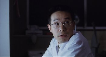 Movie still from “Gamera 3: Revenge of Iris” (1999), directed by Shûsuke Kaneko – A person wearing glasses and a white shirt; Close Up shot, Low angle