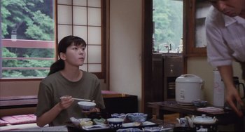 Movie still from “Gamera 3: Revenge of Iris” (1999), directed by Shûsuke Kaneko – A woman sitting at a table with bowls of food; Medium shot, Over the shoulder angle