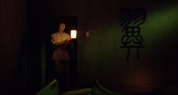 Movie still from “Gamera 3: Revenge of Iris” (1999), directed by Shûsuke Kaneko – A person standing in a room with a lamp; Medium shot, Low angle