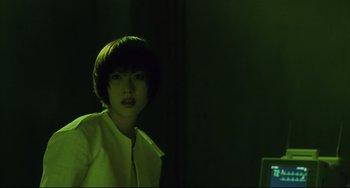 Movie still from “Gamera 3: Revenge of Iris” (1999), directed by Shûsuke Kaneko – A woman in a white shirt is standing in a dark room; Close Up shot, Low angle