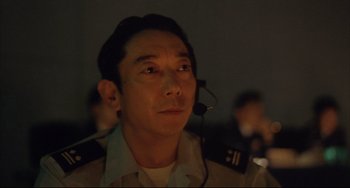 Movie still from “Gamera 3: Revenge of Iris” (1999), directed by Shûsuke Kaneko – A man with a headset in a dark room; Close Up shot, Low angle