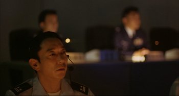 Movie still from “Gamera 3: Revenge of Iris” (1999), directed by Shûsuke Kaneko – A man with a headset in front of two other men; Close Up shot, Low angle