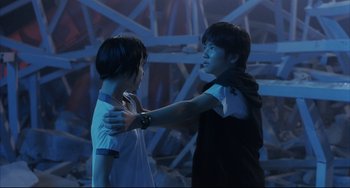 Movie still from “Gamera 3: Revenge of Iris” (1999), directed by Shûsuke Kaneko – Two young people are standing together in a room; Medium shot, Over the shoulder angle
