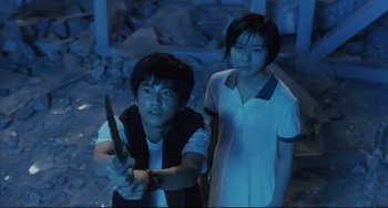 Movie still from “Gamera 3: Revenge of Iris” (1999), directed by Shûsuke Kaneko – A man and a woman standing next to each other holding a knife; Medium shot, High angle