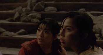 Movie still from “Gamera 3: Revenge of Iris” (1999), directed by Shûsuke Kaneko – Two women sitting next to each other in front of steps; Close Up shot, Low angle