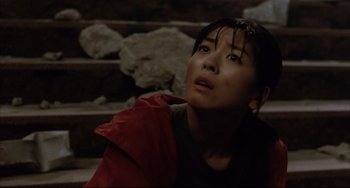 Movie still from “Gamera 3: Revenge of Iris” (1999), directed by Shûsuke Kaneko – A woman in a red jacket looking up at the sky; Close Up shot, High angle