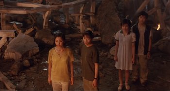 Movie still from “Gamera 3: Revenge of Iris” (1999), directed by Shûsuke Kaneko – A group of people standing next to each other in a cave; Wide shot, High angle