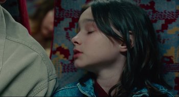 Movie still from “Aftersun” (2022), directed by Charlotte Wells – A young girl is sleeping on a blanket; Close Up shot, Over the shoulder angle