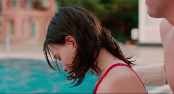 Movie still from “Aftersun” (2022), directed by Charlotte Wells – A young girl with long hair standing next to a swimming pool; Close Up shot, High angle