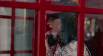 Movie still from “Aftersun” (2022), directed by Charlotte Wells – A woman talking on a phone while sitting in a booth; Close Up shot, Low angle