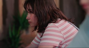 Movie still from “Aftersun” (2022), directed by Charlotte Wells – A woman with long brown hair wearing a red and white striped shirt; Close Up shot, Low angle