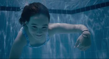 Movie still from “Aftersun” (2022), directed by Charlotte Wells – A young girl is swimming in a swimming pool; Close Up shot, Overhead angle