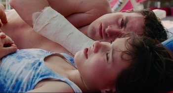 Movie still from “Aftersun” (2022), directed by Charlotte Wells – A man and a woman laying next to each other on the ground; Close Up shot, Overhead angle
