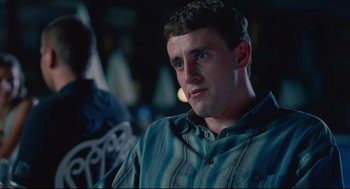 Movie still from “Aftersun” (2022), directed by Charlotte Wells – A man sitting in front of a camera in a dark room; Close Up shot, Over the shoulder angle