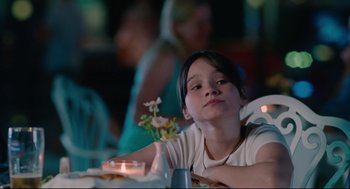 Movie still from “Aftersun” (2022), directed by Charlotte Wells – A young girl sitting at a table in front of a candle; Close Up shot, Over the shoulder angle