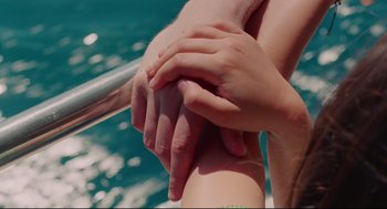 Movie still from “Aftersun” (2022), directed by Charlotte Wells – Two people holding hands on a railing in front of the ocean; Extreme Close Up shot, Overhead angle