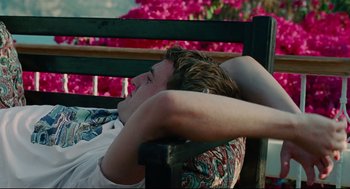 Movie still from “Aftersun” (2022), directed by Charlotte Wells – A man sitting on top of a wooden park bench; Medium shot, High angle