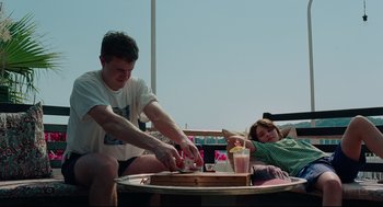 Movie still from “Aftersun” (2022), directed by Charlotte Wells – A man and a girl sitting at a table with food; Medium shot, Low angle