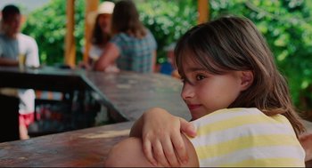 Movie still from “Aftersun” (2022), directed by Charlotte Wells – A little girl sitting at a picnic table; Close Up shot, Over the shoulder angle
