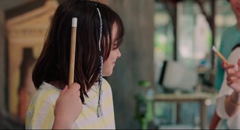 Movie still from “Aftersun” (2022), directed by Charlotte Wells – A young girl is holding a pencil in one hand and a string in the other hand; Close Up shot, Over the shoulder angle