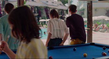 Movie still from “Aftersun” (2022), directed by Charlotte Wells – A man and a woman sitting next to each other in front of a swimming pool; Medium shot, Over the shoulder angle