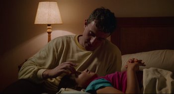 Movie still from “Aftersun” (2022), directed by Charlotte Wells – A young man and a young girl laying in a bed; Medium shot, High angle