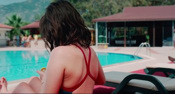 Movie still from “Aftersun” (2022), directed by Charlotte Wells – A woman in a red bikini sitting by a pool; Medium shot, High angle