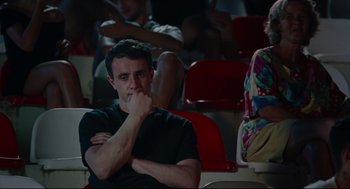Movie still from “Aftersun” (2022), directed by Charlotte Wells – A man sitting in front of a group of people; Medium shot, High angle