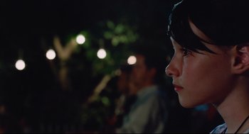 Movie still from “Aftersun” (2022), directed by Charlotte Wells – A young girl looking into the distance at night; Close Up shot, Over the shoulder angle