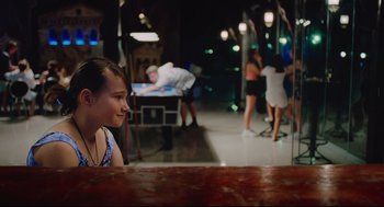 Movie still from “Aftersun” (2022), directed by Charlotte Wells – A young girl sitting at a table in front of a mirror; Medium shot, Over the shoulder angle