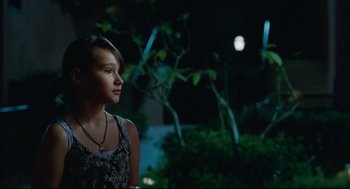 Movie still from “Aftersun” (2022), directed by Charlotte Wells – A young girl is standing in the dark outside; Close Up shot, Over the shoulder angle