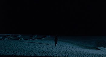 Movie still from “Aftersun” (2022), directed by Charlotte Wells – A person walking on the beach at night; Extreme Wide shot, High angle