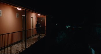 Movie still from “Aftersun” (2022), directed by Charlotte Wells – A person standing on a balcony at night; Extreme Wide shot, Low angle