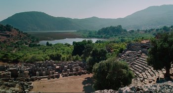 Movie still from “Aftersun” (2022), directed by Charlotte Wells – A view of a lake from above with a lot of trees in the foreground; Extreme Wide shot, High angle