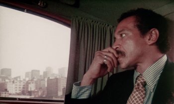 Movie still from “Ganja & Hess” (1973), directed by Bill Gunn – A man sitting in front of a window on a cell phone; Close Up shot, Low angle