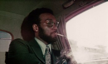 Movie still from “Ganja & Hess” (1973), directed by Bill Gunn – A man smoking a cigarette while sitting in a car; Close Up shot, Low angle