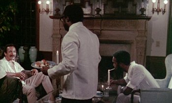 Movie still from “Ganja & Hess” (1973), directed by Bill Gunn – A group of people sitting around a table with food on it; Medium shot, Over the shoulder angle