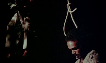 Movie still from “Ganja & Hess” (1973), directed by Bill Gunn – A man with a noose around his neck and holding a knife; Close Up shot, Low angle