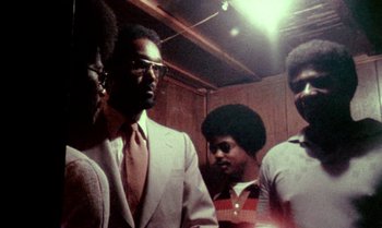 Movie still from “Ganja & Hess” (1973), directed by Bill Gunn – A group of men standing next to each other in a room; Medium shot, Low angle