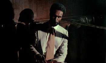 Movie still from “Ganja & Hess” (1973), directed by Bill Gunn – A man wearing a suit and tie holding a glass of wine; Medium shot, Low angle