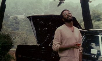 Movie still from “Ganja & Hess” (1973), directed by Bill Gunn – A man standing in front of an open trunk; Medium shot, Low angle