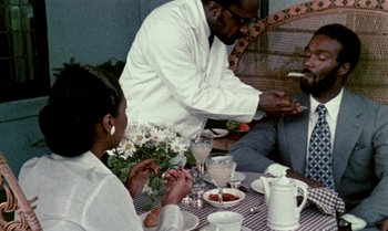 Movie still from “Ganja & Hess” (1973), directed by Bill Gunn – Three people are sitting at a table with food; Medium shot, Over the shoulder angle