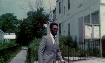 Movie still from “Ganja & Hess” (1973), directed by Bill Gunn – A man in a suit and tie walking down a sidewalk; Wide shot, Low angle