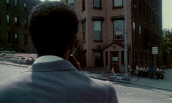 Movie still from “Ganja & Hess” (1973), directed by Bill Gunn – A man in a gray jacket is talking on a cell phone; Wide shot, Over the shoulder angle