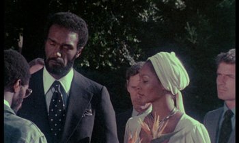 Movie still from “Ganja & Hess” (1973), directed by Bill Gunn – A man and a woman standing next to each other in front of a tree; Medium shot, Low angle
