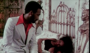 Movie still from “Ganja & Hess” (1973), directed by Bill Gunn – A man and a woman are sitting on a bed; Medium shot, Low angle
