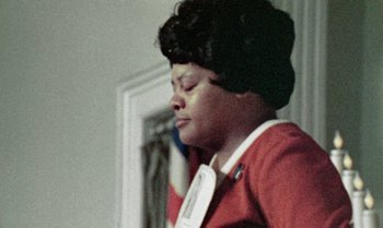 Movie still from “Ganja & Hess” (1973), directed by Bill Gunn – A woman in a red jacket is looking down; Close Up shot, Low angle