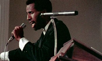 Movie still from “Ganja & Hess” (1973), directed by Bill Gunn – A man is holding a microphone up to his ear; Close Up shot, Low angle